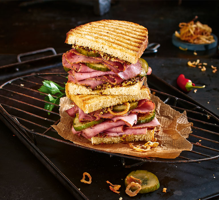 XXL Geflügel-Pastrami-Sandwich auf einem Grillrost angerichtet