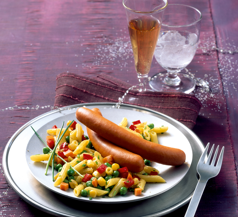 Geflügel-Wiener mit Gemüse-Nudelsalat auf einem Teller serviert